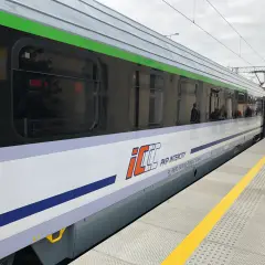 Pociąg PKP Intercity z charakterystycznym logo eip stoi na peronie.