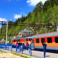Pociąg PKP Intercity na stacji, podróżni czekają na peronie. W tle zielone wzgórza, idealne na wycieczkę z Koszalina do Czaplinka.