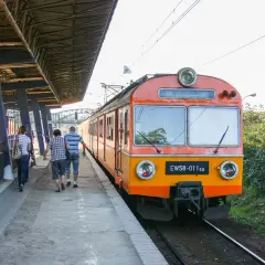 Pasażerowie idą wzdłuż peronu do pociągu EW58-011sa, który czeka na odjazd.