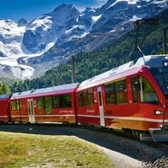 Czerwony pociąg Bernina Express na malowniczej trasie wśród alpejskich szczytów i zielonych lasów.