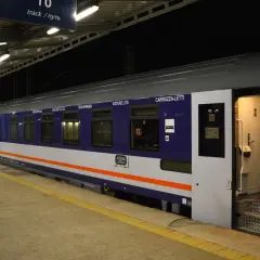 Nocny pociąg z wagonami sypialnymi, takimi jak CARROZZA-LETTI, czeka na pasażerów na peronie.