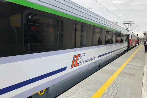 Pociąg PKP Intercity z charakterystycznym logo eip stoi na peronie.