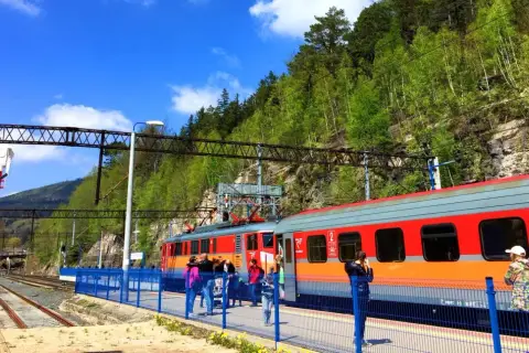 Pociąg PKP Intercity na stacji, podróżni czekają na peronie. W tle zielone wzgórza, idealne na wycieczkę z Koszalina do Czaplinka.