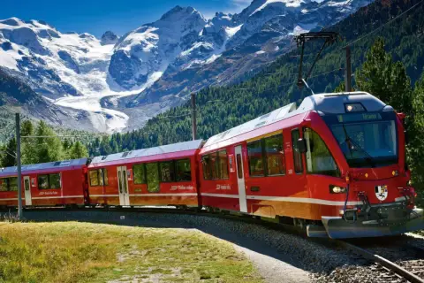 Czerwony pociąg Bernina Express na malowniczej trasie wśród alpejskich szczytów i zielonych lasów.