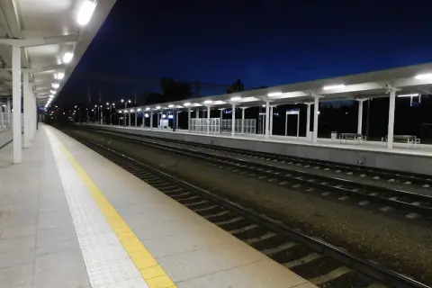 Pusta stacja kolejowa nocą, tory i perony oświetlone lampami. Czekam na pociąg do Krakowa lub Bochni.