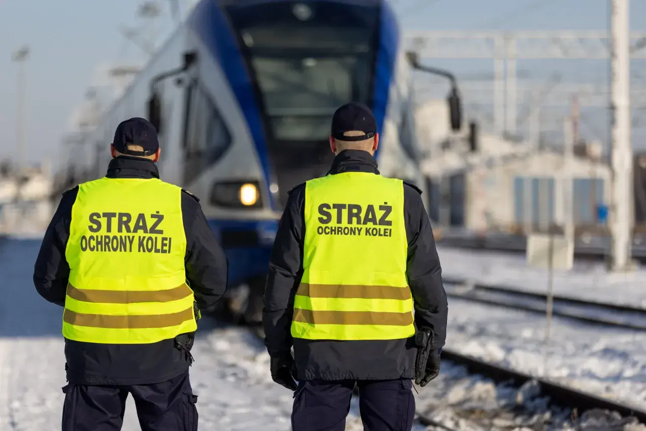 Dwóch funkcjonariuszy Straży Ochrony Kolei w kamizelkach odblaskowych stoi przed pociągiem. Czy mogą wystawić mandat?