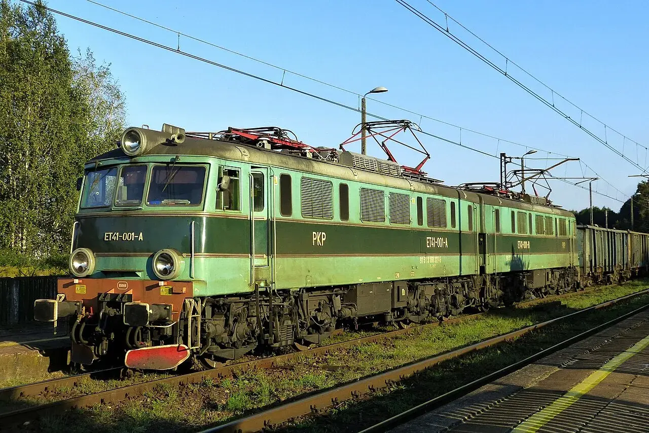 Zielona lokomotywa ET41 PKP z wagonami towarowymi na torach.
