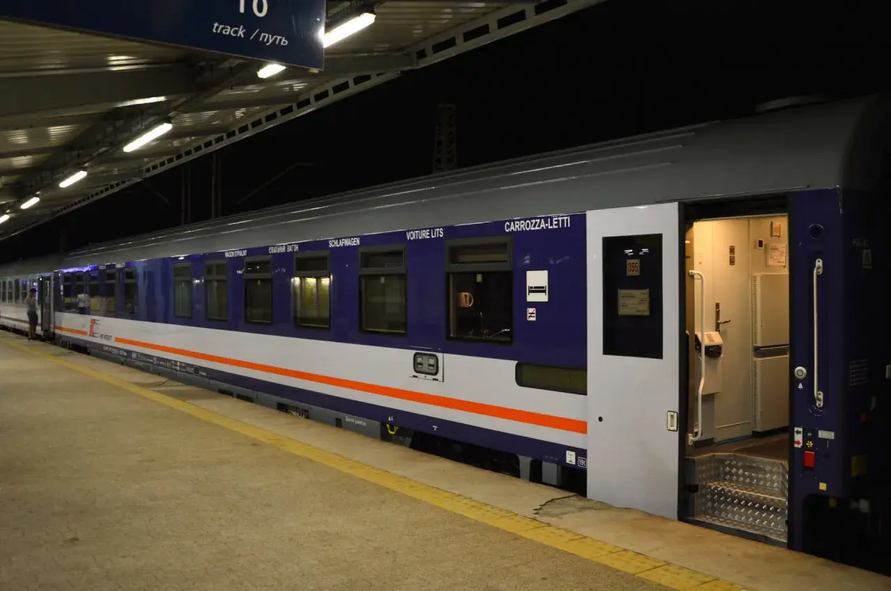 Nocny pociąg z wagonami sypialnymi, takimi jak CARROZZA-LETTI, czeka na pasażerów na peronie.