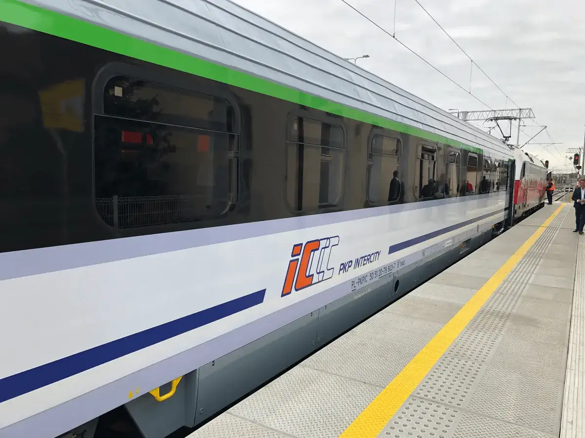 Pociąg PKP Intercity z charakterystycznym logo eip stoi na peronie.