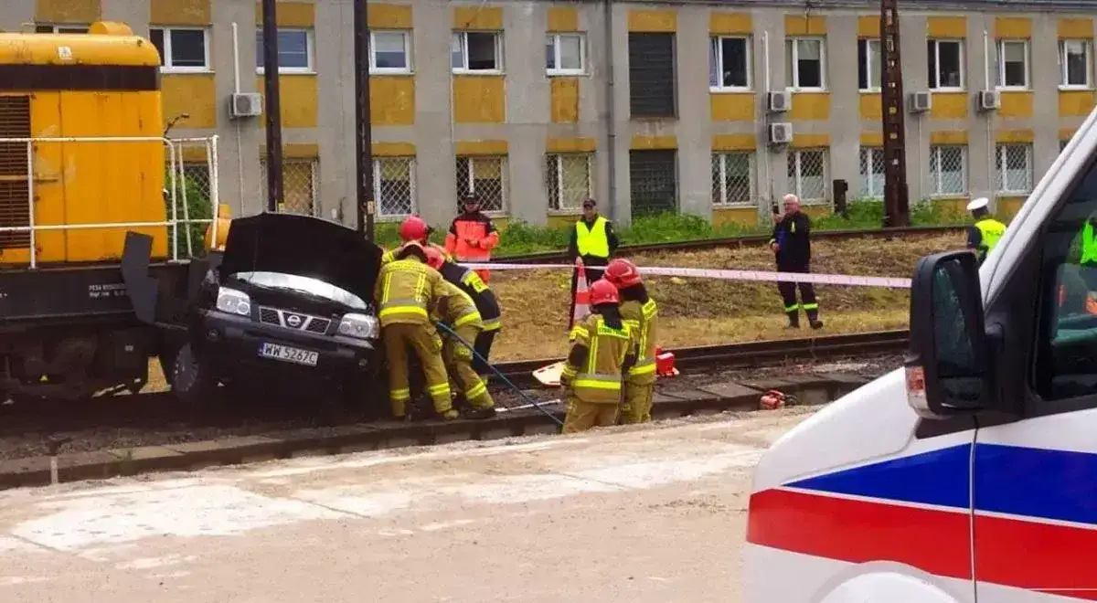 Strażacy ratują kierowcę po wypadkach kolejowych. Czarny samochód wjechał na tory i zderzył się z lokomotywą.