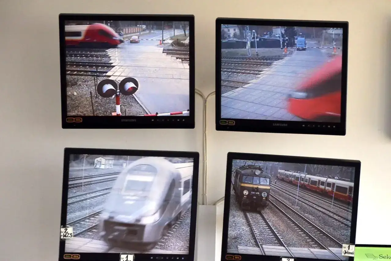 Monitoring PKP: cztery monitory pokazują przejazdy kolejowe i pociągi w ruchu.