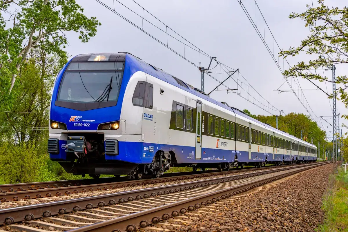 Nowy pociąg ED160 PKP Intercity mknie po torach wśród zieleni.